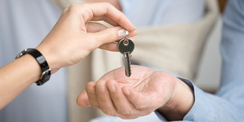 Close up of two hands with realtor handing house key over