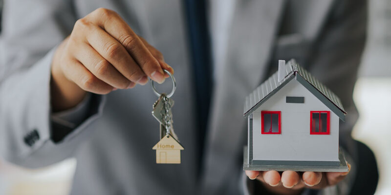 Loan officers hands out holding a toy house and keys