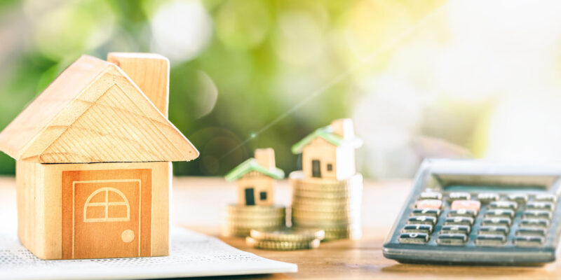 toy house with calculator and stack of coins