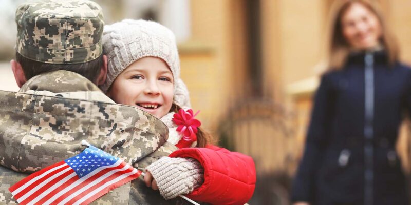 veteran hugging child with wife in background