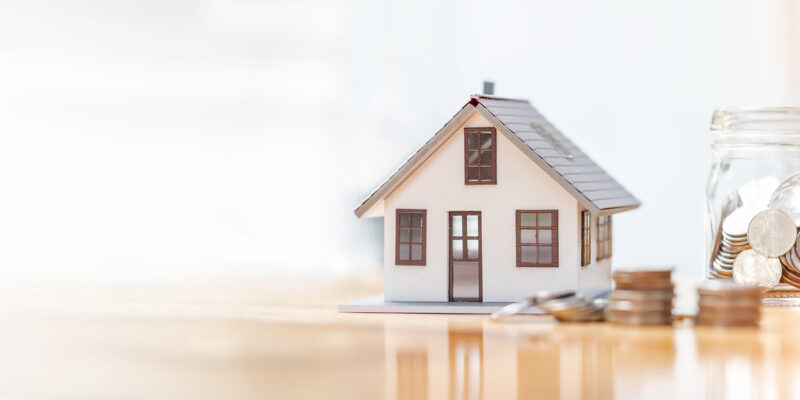 Toy house and coins on desk