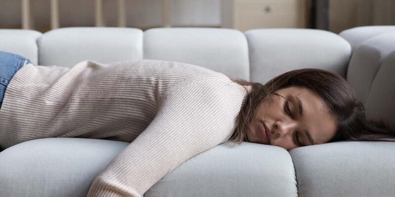 Exhausted female laying on couch from homebuyer fatigue
