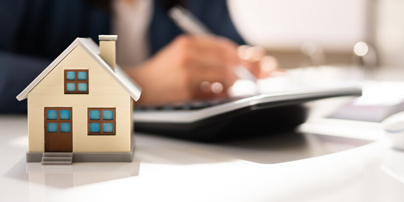 Toy house in front of calculator on a desk