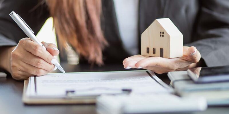 Female signing documents with toy house in her hand