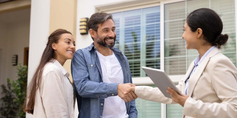 Realtor shaking hands with client outside house