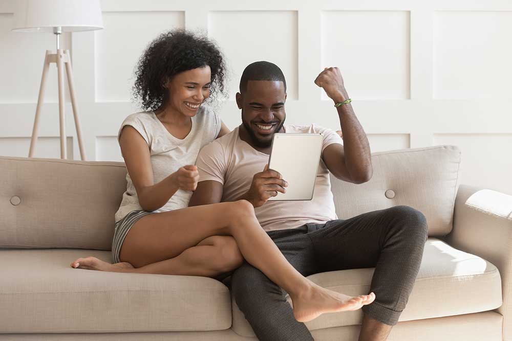 Young couple on a laptop celebrating good news