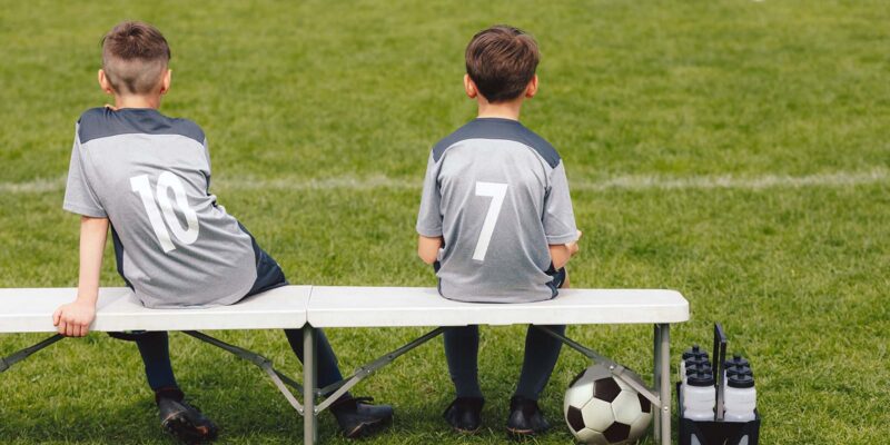 kids sitting on soccer bench