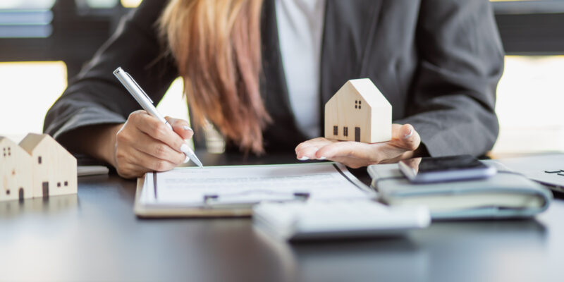 Female signing documents with toy house in her hand