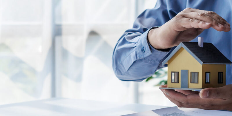 Hand over toy house protecting it